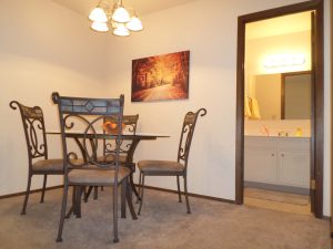 Dining table and four chairs next to a door open to a bathroom