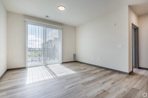 an empty apartment living room with screen doors to a balcony