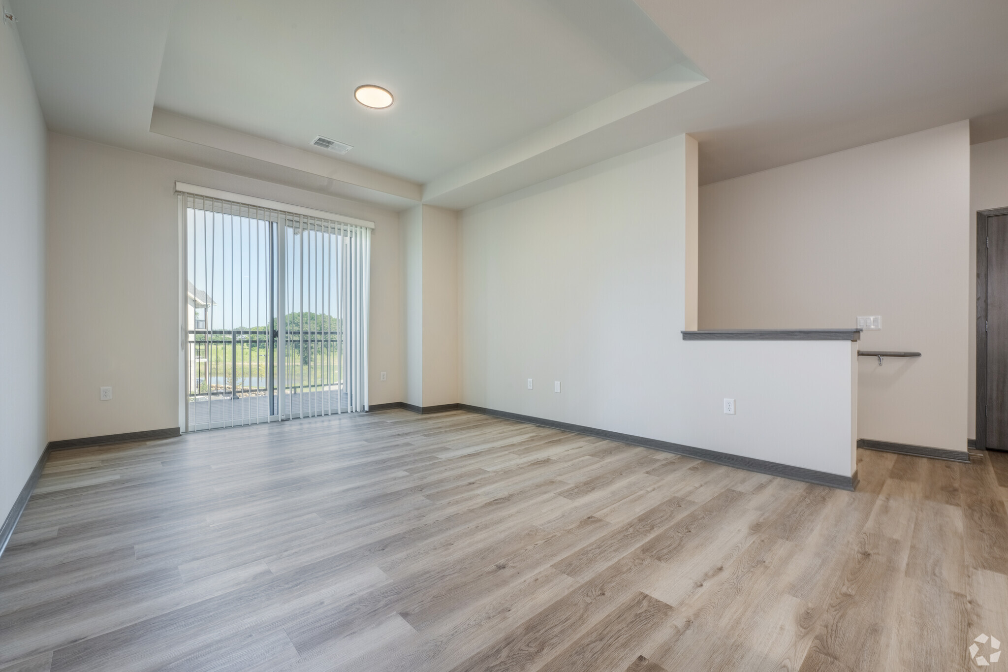 an empty apartment living room with window doors and a staircase